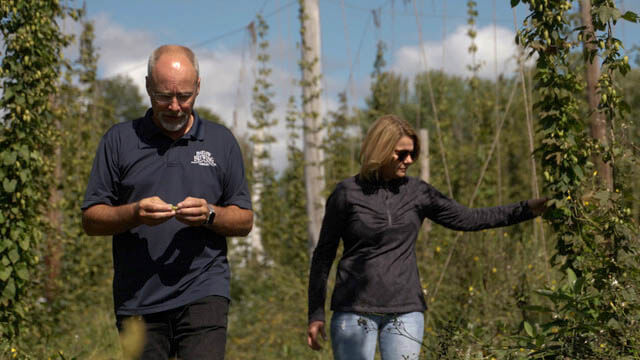 Jeff and Pam Powers walking among the hops